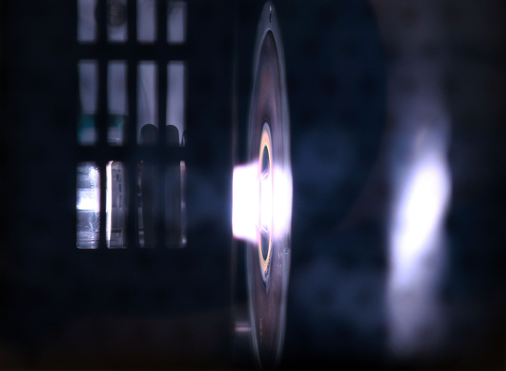 Das Foto zeigt die Brennerdüse im Inneren eines ICP-MS-Messgeräts. Aus der Brennerdüse tritt ein heller Lichtkegel.
