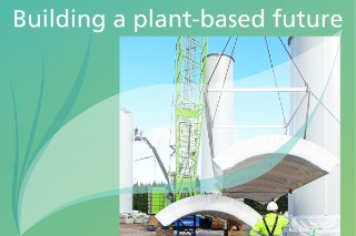 The symbolic image shows the construction of a wind turbine tower.