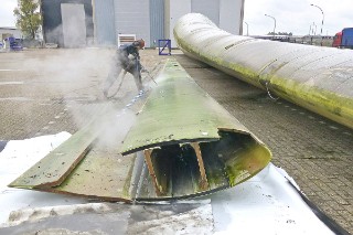 The photo shows a wind turbine rotor blade that has been cut open and is largely hollow on the inside. The shell is reinforced with dark gray material in the middle area along the entire length of the rotor blade.