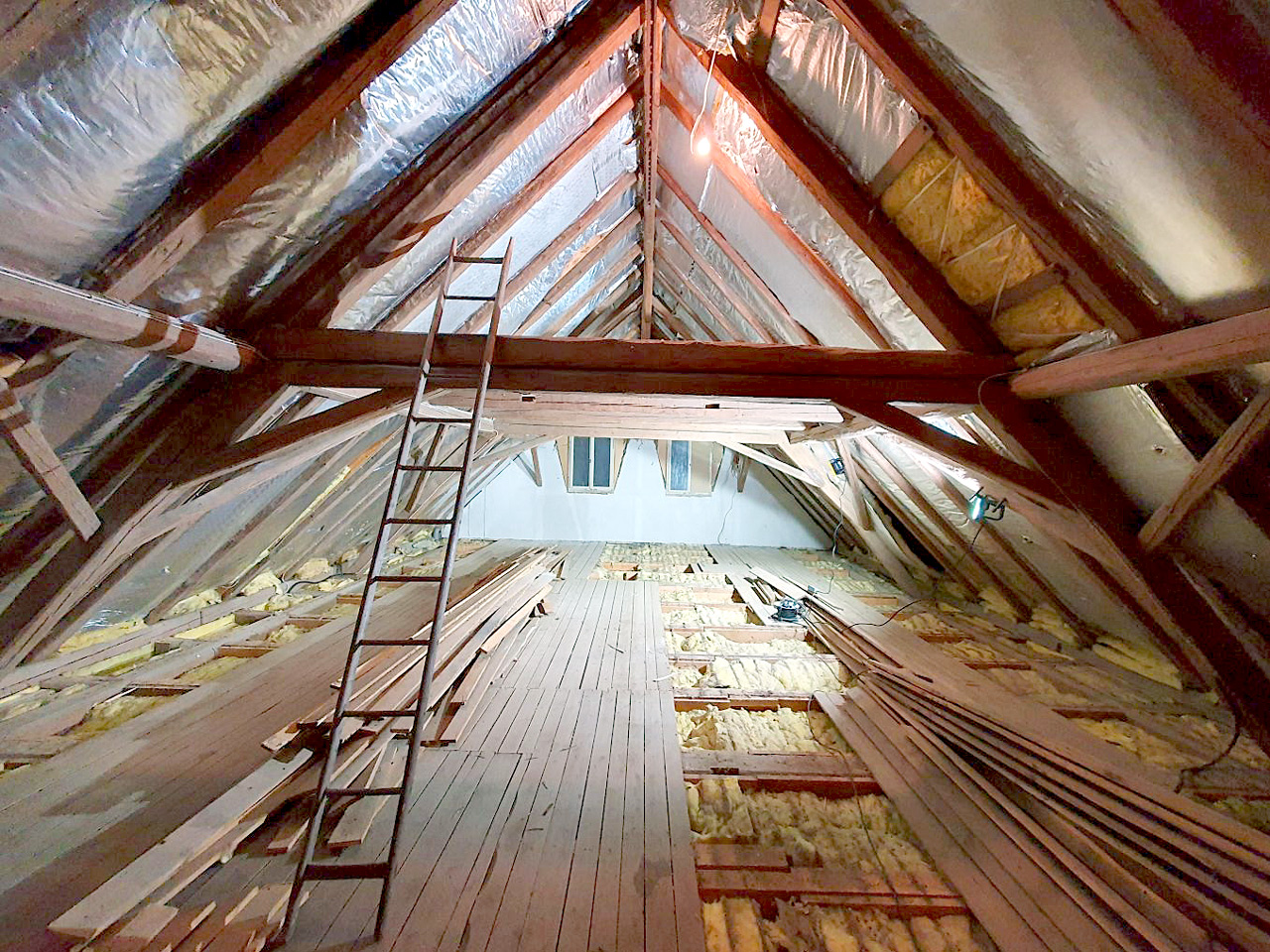 The photo shows the interior view of a roof truss with exposed, dark-brown wooden beams.