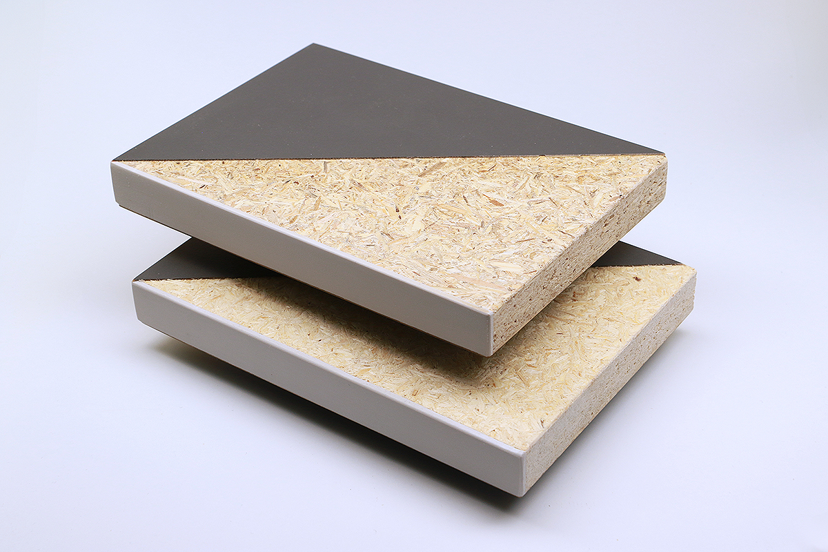 The photo shows two partially coated pieces of particle board that look almost identical. Some of the wood chips on the upper board are slightly darker.